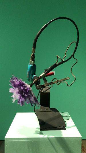 A video of an old electric drill with a purple duster attached at a distance. As the video starts, the duster begins to spin.